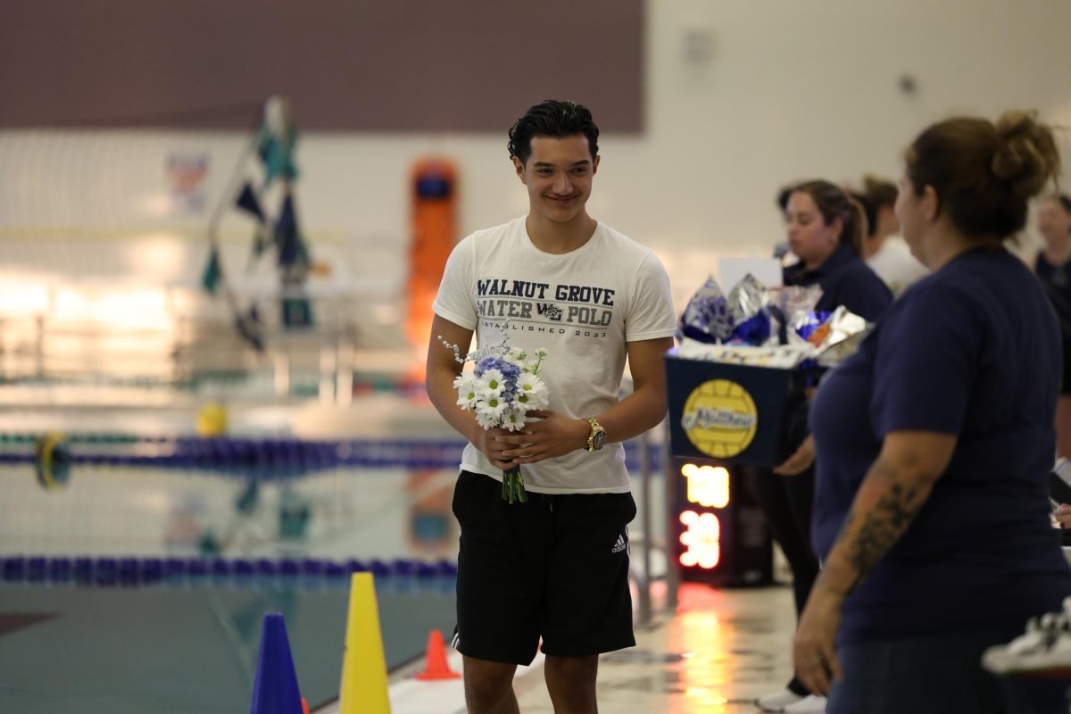 Smiling at his family, Matthew Amelines, a senior varsity water polo player receives recognition for senior night. Amelines along with the other senior water polo players were presented with a gift bag and flowers. Other varsity water polo players wrote letters for the seniors before the game, thanking them for their help and encouragement.