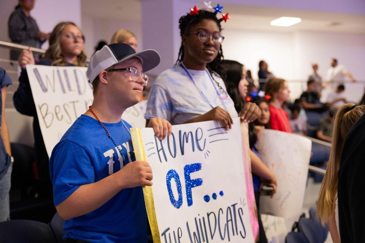 With handmade signs, sophomore Dane Miller (left) and freshman Ava Fatiregun (right) stand at the USA pep rally promoting school spirit. The Best Buddies club attended the event together. The next Walnut Grove pep rally is October 4th for the forthcoming football game.