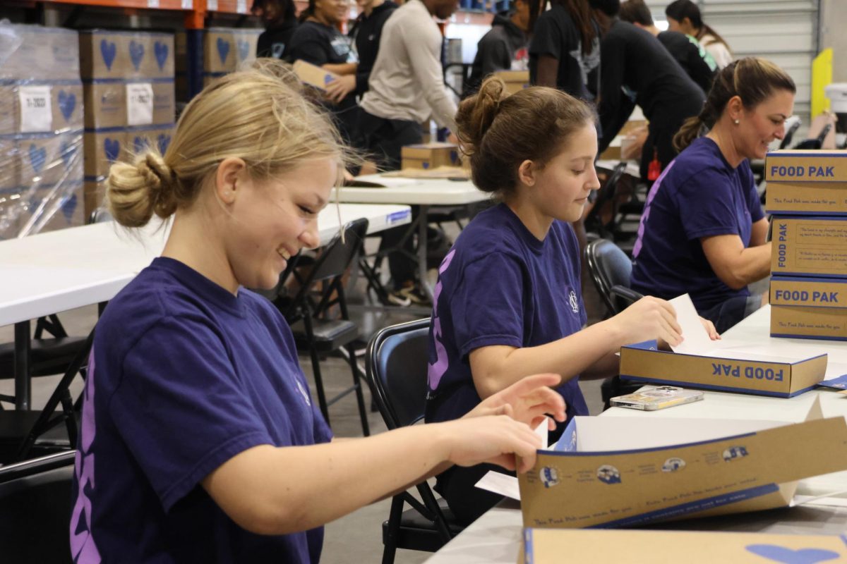 Chatter fills the warehouse as sophomores Maddie Wooten and Lauren Fields build each box for the Food Paks that will later be filled with food to feed suffering children. 