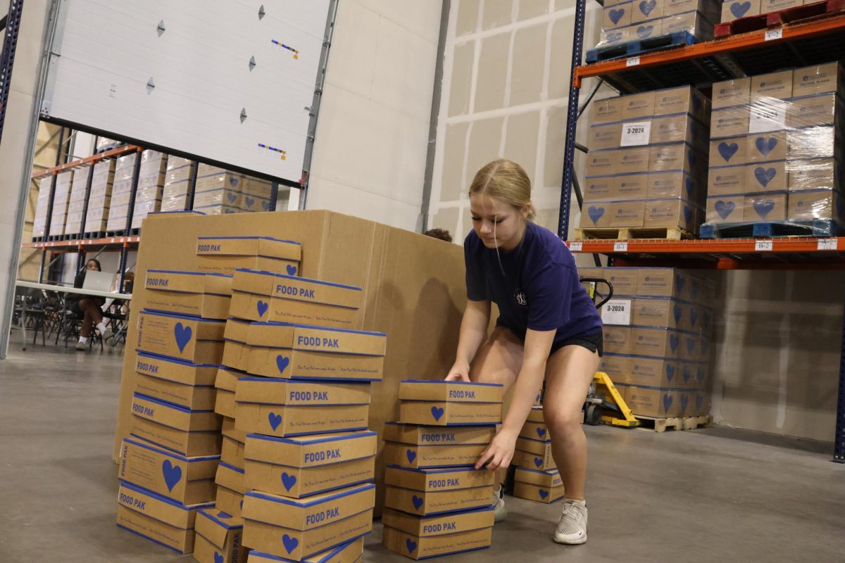 Boxes all around, sophomore Lauren Fields re-organizes the boxes. The previously stacked boxes needed to be removed to be turned vertical in order to fit better. This allows for more boxes to be packed with food.