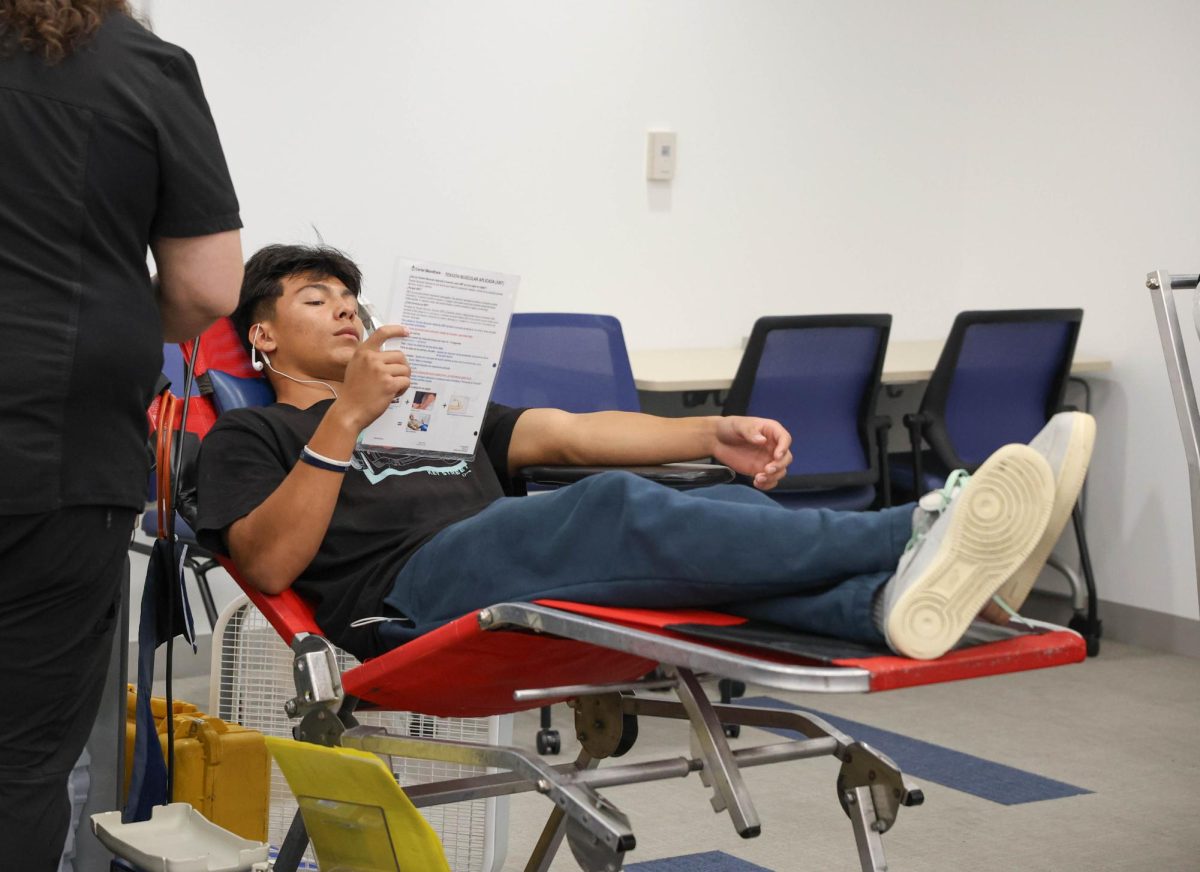 While the nurse preps the needles, senior Enoch Alvarenga reads the sheet that informs students on their blood donation process. Students must be at least 17 years old in order to give blood, limiting the able students to only some juniors and most seniors. 