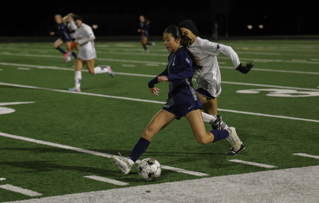 Ready to pass the ball, No. 1 freshman Ava Kim tries to outrun Sachse player. The Walnut Grove varsity girls soccer team played against Sachse High School Tuesday, Jan. 9. Walnut Grove players wore orange ribbons in their hair to support Leukemia Awareness. 