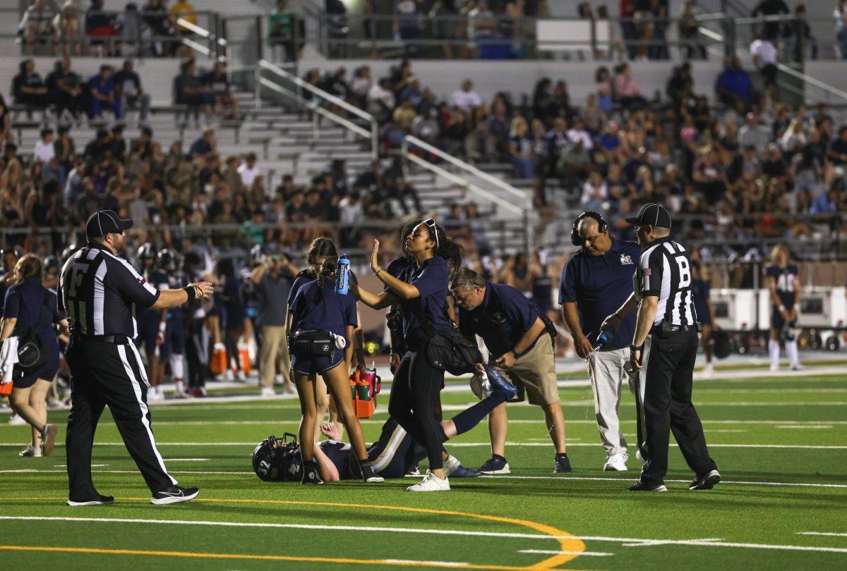 Senior Chloe Moore helps No. 32 on the Little Elm varsity team. Walnut Grove played against Little Elm Sep. 7.  The player had a hamstring issue and Moore ran out to help and made sure people stayed away, so the athlete could have space. “One of my favorite things about this program is being able to see the injured athletes go back and play the game that they love,” Moore said. 

