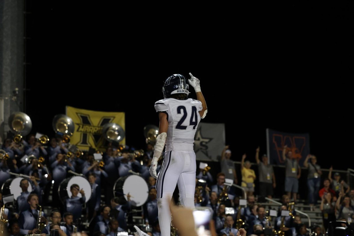 Standing in front of the band, senior Noah Sallaway, No. 24, raises his hand to honor the WGHS alma mater after an exciting win against Emerson High school Thursday., Sept. 12.