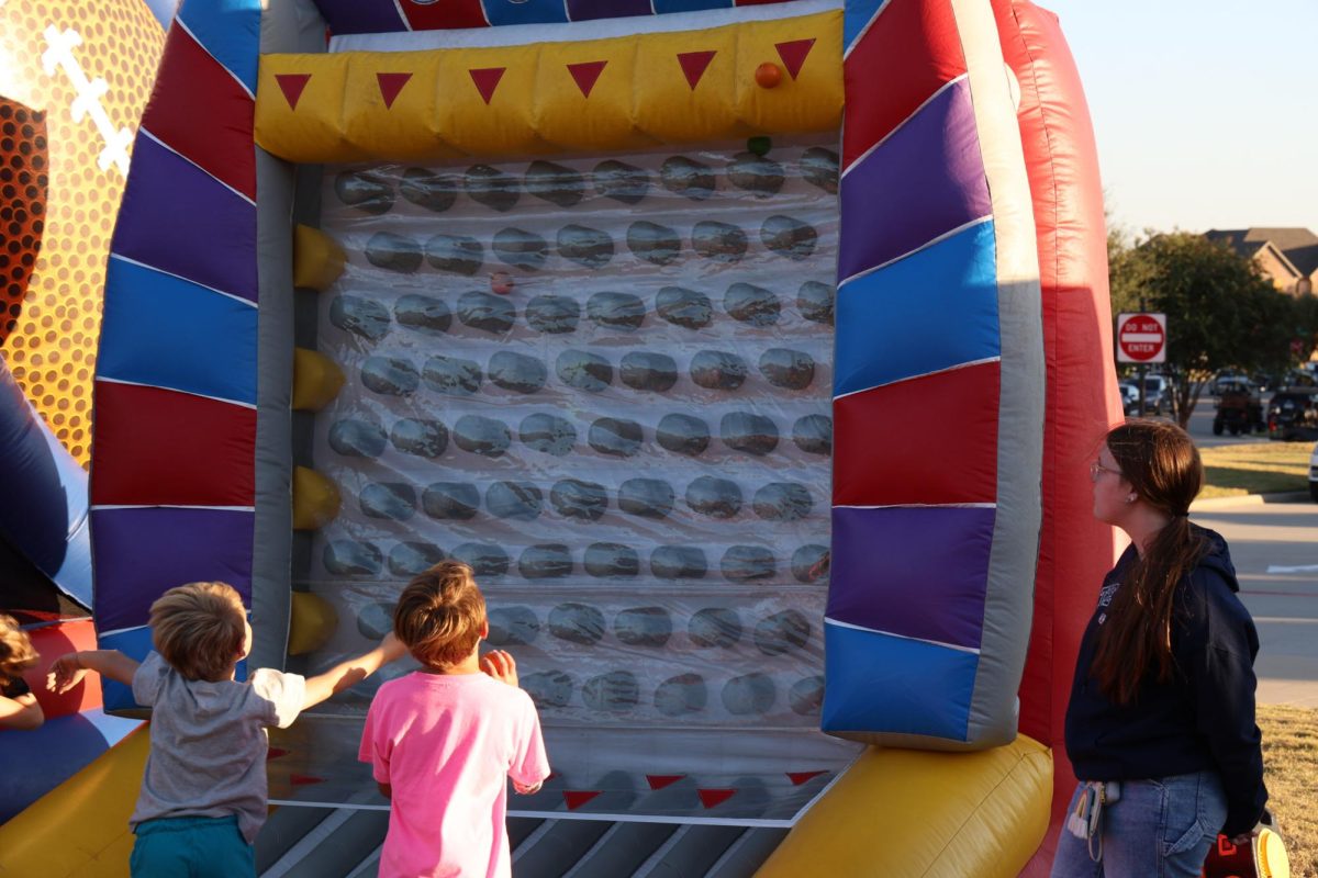 Senior Chloe Diaz looks up, watching the elementary student throw the balls up the inflatable wall.