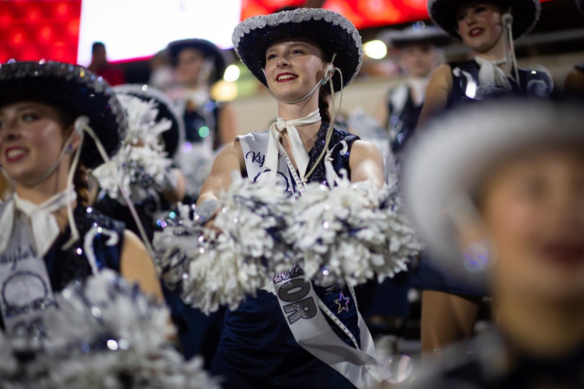 Arms stretched out, senior Kylie Barnes shakes her poms as she cheers on varsity football at their senior night game against Newman Smith. "Nothing can top performing in front of a stadium full of people," Barnes said. This photo was taken by Scott Albrecht, Silver Elites photographer. 
