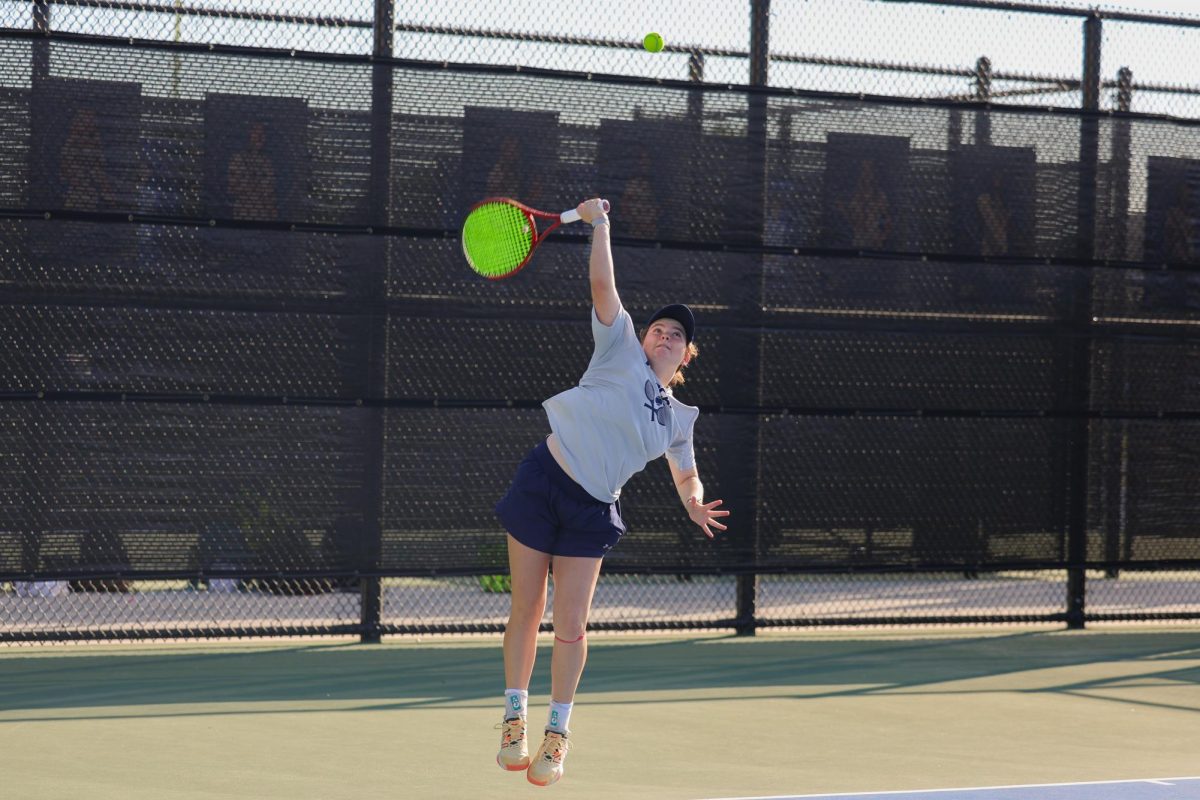 In the air, senior Nicole Steel prepares to hit the ball across the court. "I think I'm most proud of participating in tennis," Steel said. "At the beginning of last year, our team had no culture, no traditions, and was starting from scratch. I’m proud to say that now as a team we have all of that, and we have a winning culture that fosters all of the little things our coaches consider important." This photo was taken at the 2023 senior tennis night. 