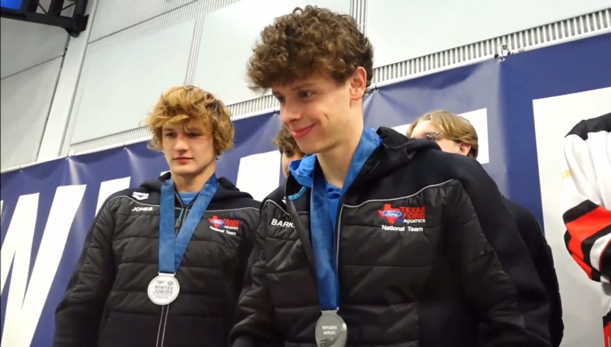 Barker and his teammate were awarded with a medal after they received second place at a Junior National swim meet. In the picture, Barker is shaking the medal-giver's hand.
