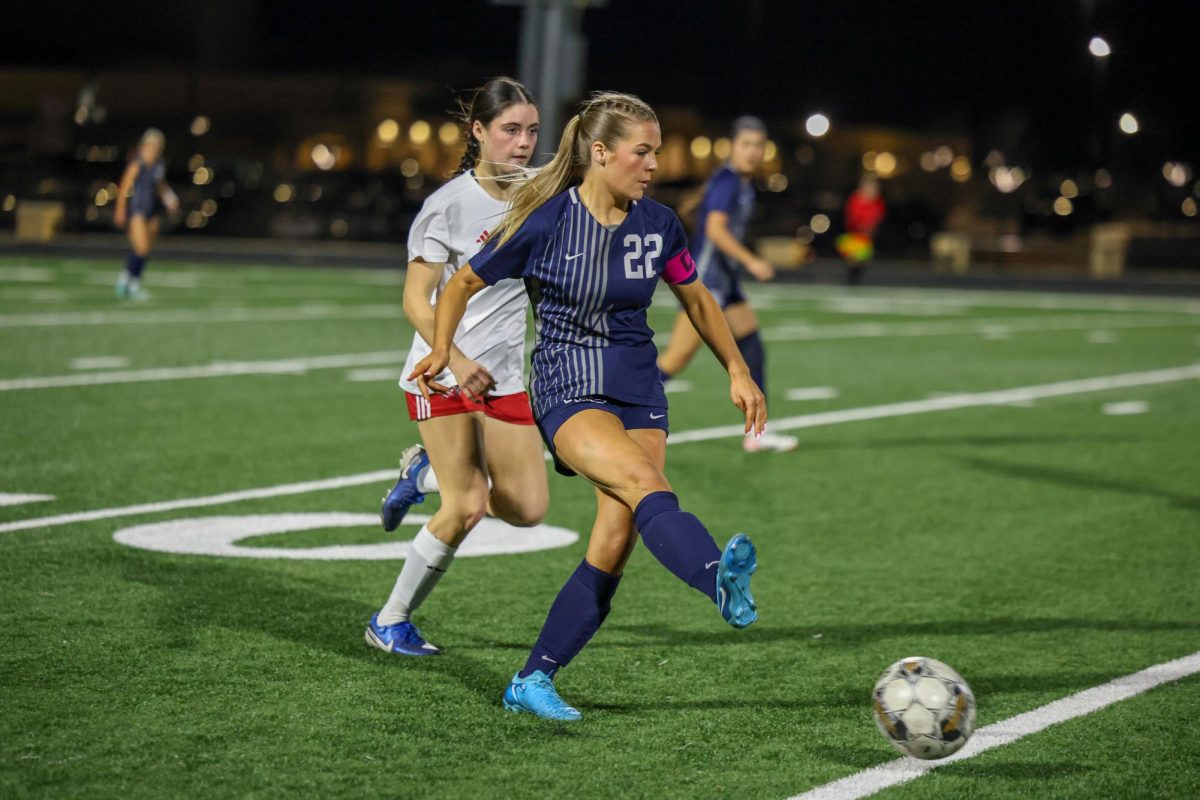 Foot foward, No. 22 senior Quinn Wolfe kicks the ball towards her teammate. 