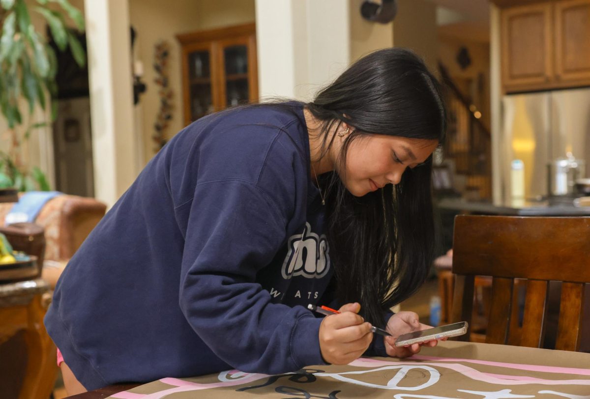 Ava Tran finishes up a martini glass design on a banner for one of her customer's twenty-second birthday.