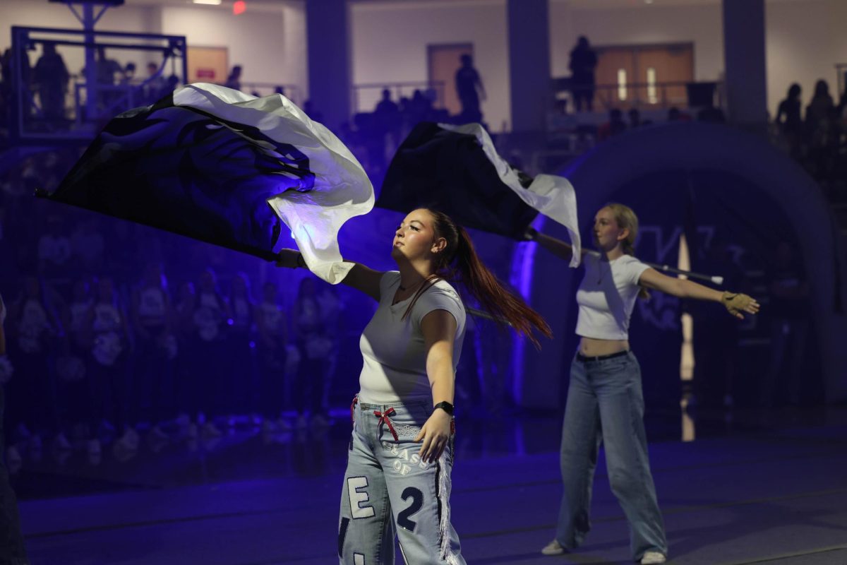 Aly Fallwell, a color guard performer, performs gracefully with a flag in hand. 