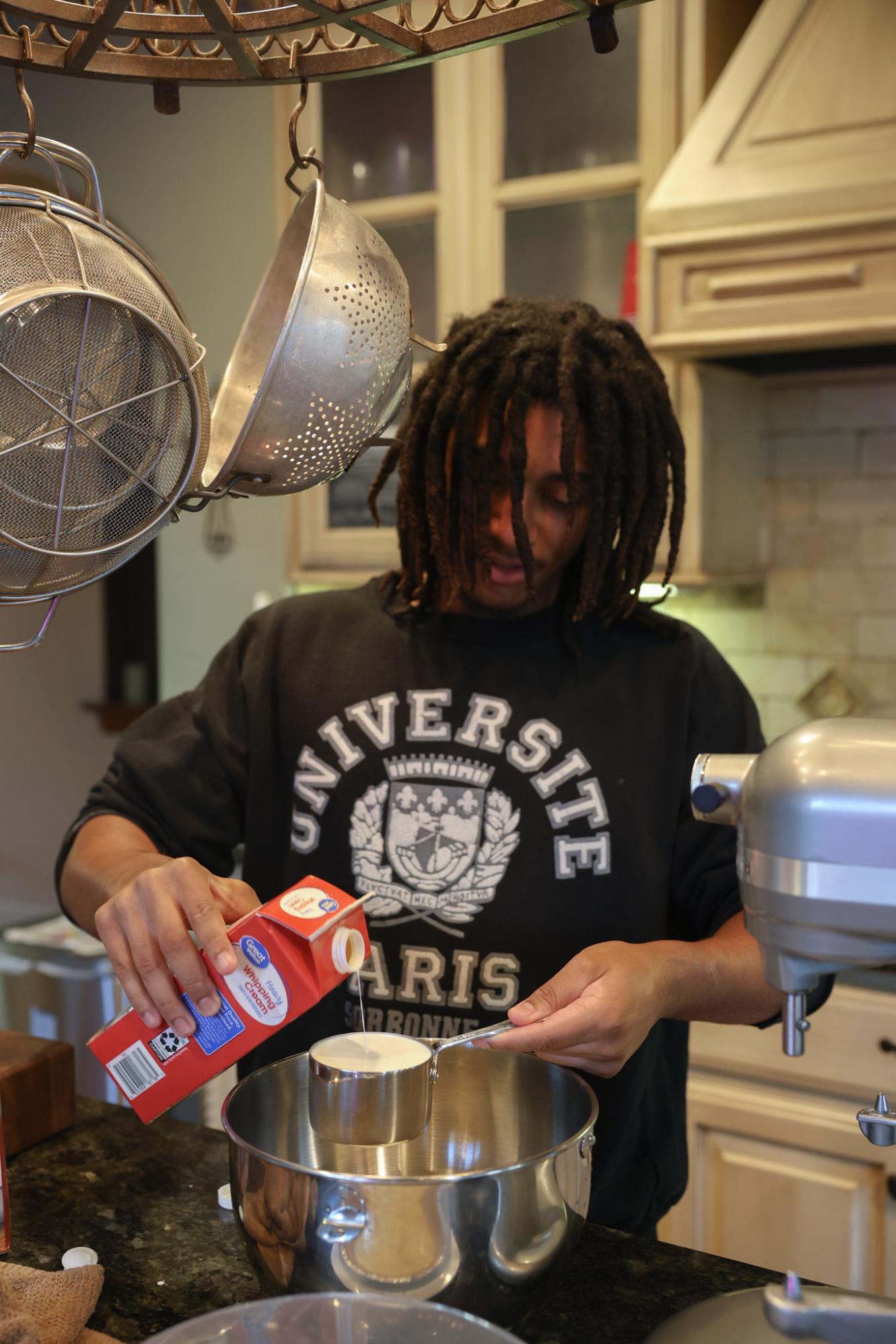 Noah Rose pouring heavy whipping cream to make the whipped cream for his key lime pie.