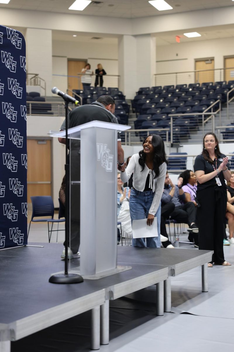 Senior Srinithi Manjunath grins with gless as she accepts her recognition L.E.A.D.E.R.S award.