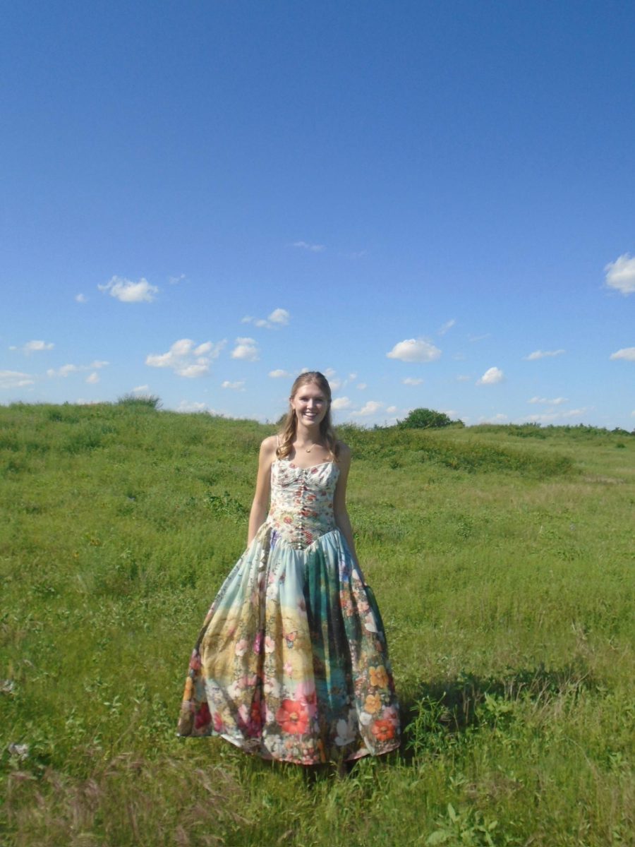 Standing in a field, Senior Chloe Bernecker smiles widely at the camera. (Credits to Chloe Bernecker)